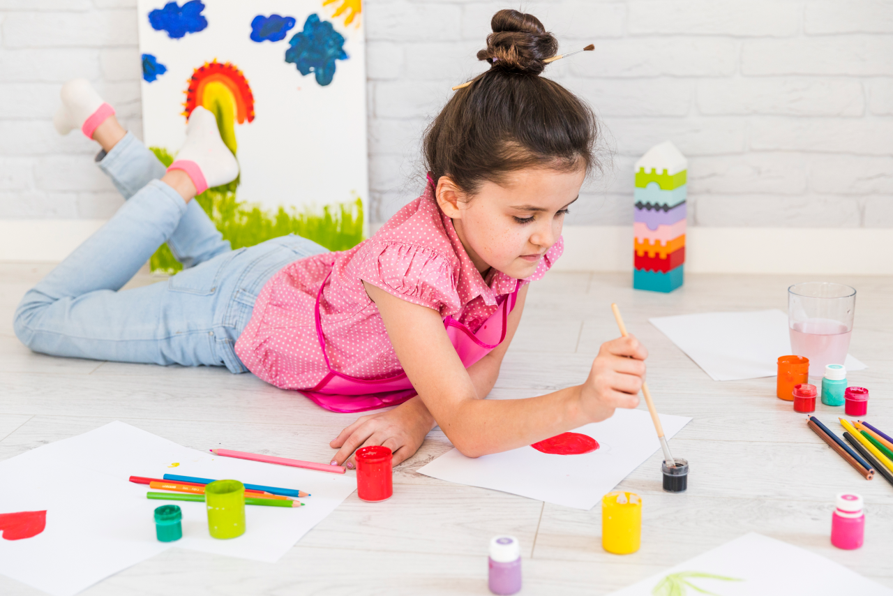 little-girl-lying-floor-painting-with-water-color-with-paint-brush-paper 1.png